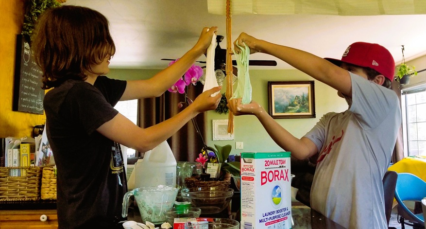 Brothers doing a borax and shaving cream slime homeschool science experiment.